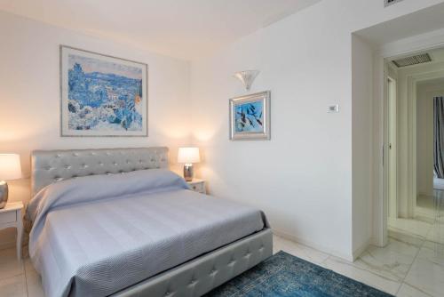 a white bedroom with a bed and two lamps at Villa Bianca Luxury Apartments in Desenzano del Garda