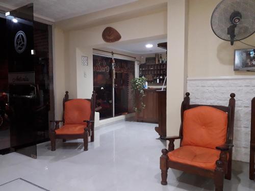 a lobby with two orange chairs and a fireplace at Hotel Antonia in Termas de Río Hondo