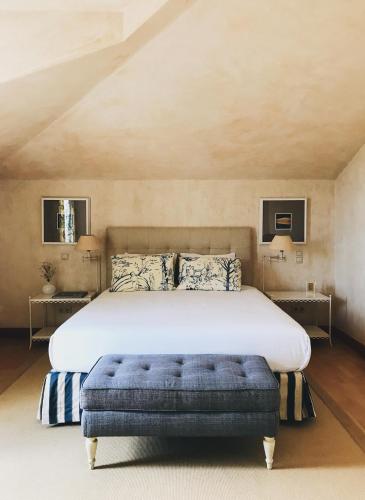a bedroom with a large bed and a blue ottoman at Quinta De Catralvos in Azeitao