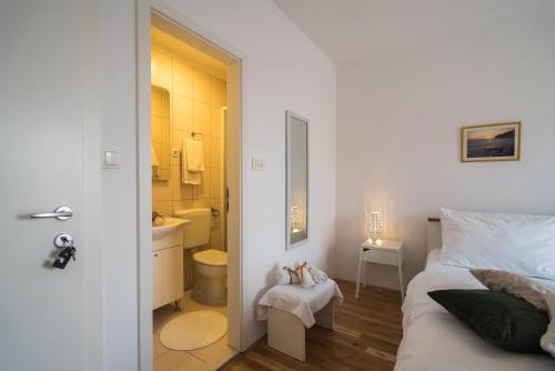 a white bedroom with a bed and a bathroom at Guest house Lana in Split