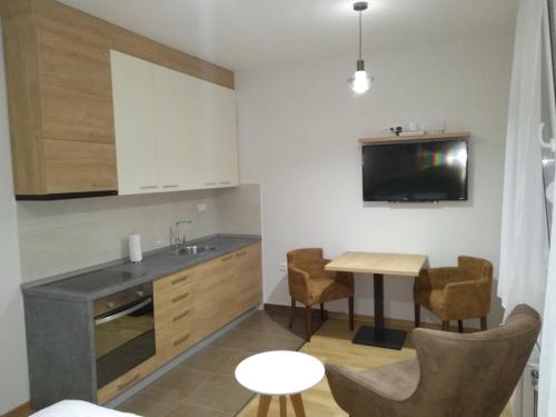 a kitchen with a table and a tv on the wall at NM Apartman in Banja Luka