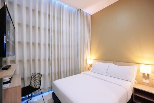 um quarto com uma cama, uma secretária e uma televisão em Figtree Hotel em Iloilo