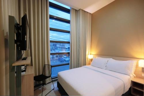 Habitación de hotel con cama y ventana en Figtree Hotel, en Iloilo City