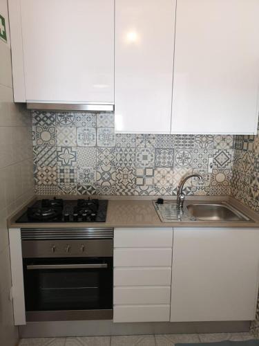 a kitchen with white cabinets and a stove and a sink at Casa João Bravo in Albufeira