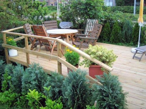 a wooden deck with chairs and a table in a garden at Haus Jungnamen Sand Whg. 14 in Wittdün