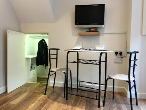 a room with two chairs and a table with a tv on the wall at BexLet in Bexhill