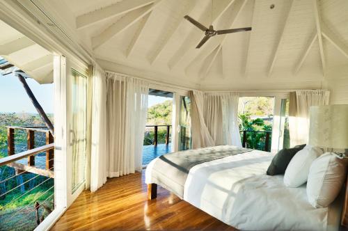 a white bedroom with a bed and a balcony at Mikado Natural Lodge in Playa Avellana