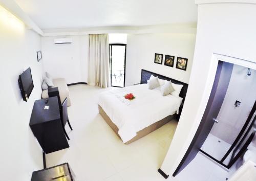 a white bedroom with a bed and a television at Hotel Oasis in Nadi