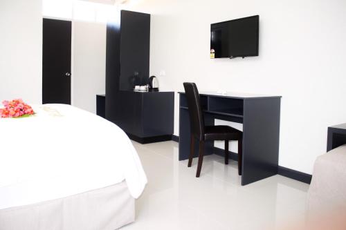 um quarto com uma secretária, uma cama e uma televisão em Hotel Oasis em Nadi