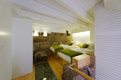 a bedroom with two beds and a stone wall at Guimarães Studios Lounge in Guimarães
