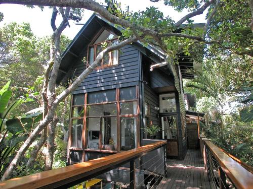 a black house with a deck in the trees at Shambhala @ Byron in Byron Bay