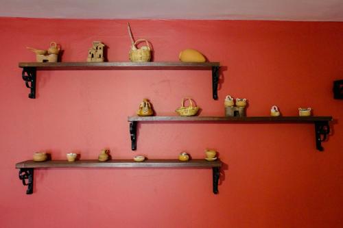 a red wall with wooden shelves with purses and baskets at Hotel Margarita in Puno