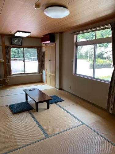 a room with a table and two windows at Minshuku Sumiya in Tanabe