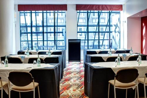 a row of tables in a room with windows at Adina Citylife Auckland in Auckland