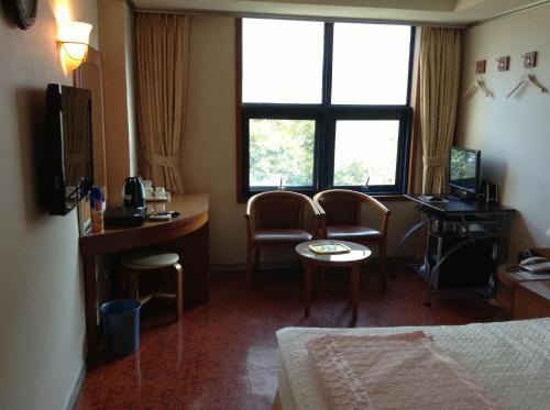 a hotel room with a bed and a desk and chairs at Mirabell Motel in Busan