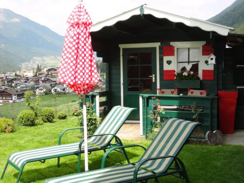 two chairs and an umbrella in front of a house at Alpenferienwohnung Strickner in Neustift im Stubaital