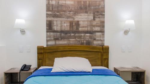 a bedroom with a bed with a wooden headboard at Hotel Ciudad Latin Palace in Guayaquil