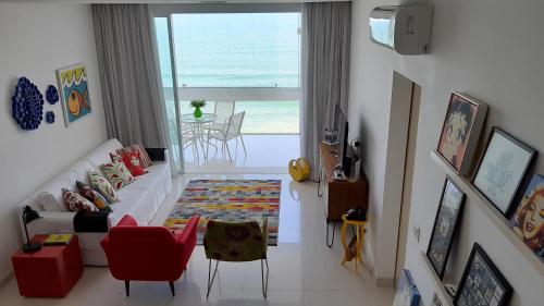 a living room with a couch and a view of the ocean at Pitangueiras - Apto. Frente Mar in Guarujá