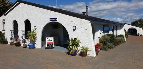 a white building with potted plants in front of it at Barrington House Taupo in Taupo