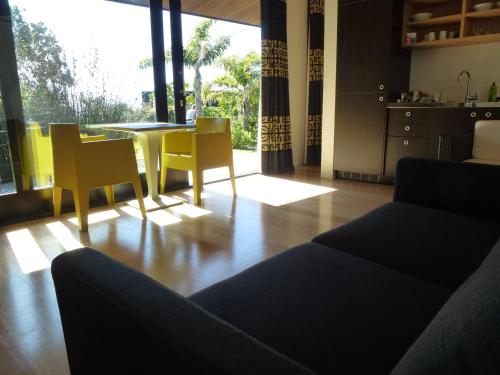 uma sala de estar com um sofá, uma mesa e cadeiras em Hot Water Beach Bure Wai em Hotwater Beach