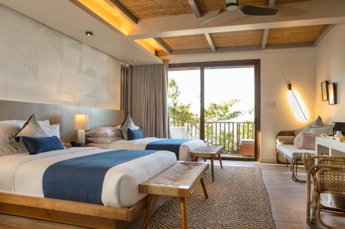 a hotel room with two beds and a balcony at Maremegmeg Beach Club in El Nido
