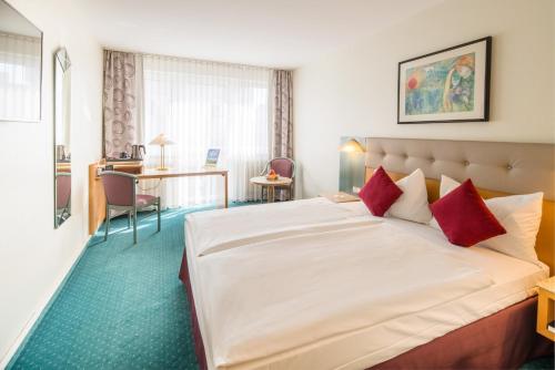 a hotel room with a large bed with red pillows at PLAZA Hotel Blankenburg Ditzingen, Sure Hotel Collection in Ditzingen