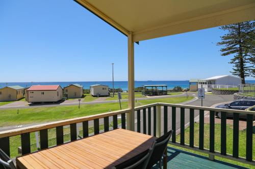 a balcony with a table and a view of the ocean at Bulli Beach Tourist Park in Bulli