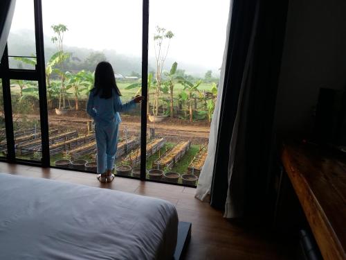 a woman looking out the window of a room at Him doy muang pan resort ฮิมดอยเมืองปานรีสอร์ท in Ban Sop Pan