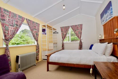 a bedroom with a bed and two windows at Waragil Cottage - Original Settler's Home in Blackheath