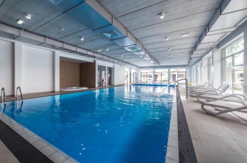 a large swimming pool with chairs in a building at Family-Holiday Spa&Resort in Dziwnówek