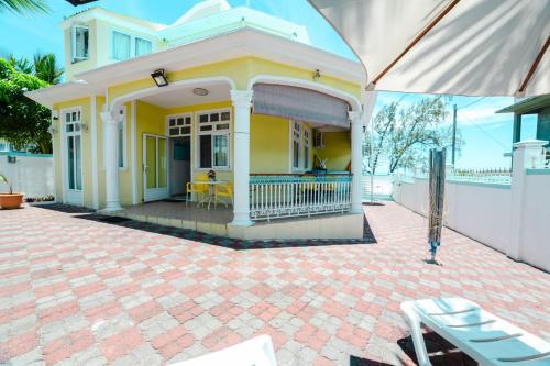 a yellow house with a porch and a patio at Villa Bella Charming Beachfront Guesthouse in Blue Bay