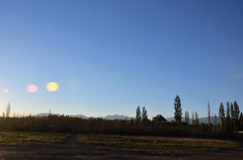a sunset over a field with trees and a dirt road at El Pasaje in Malargüe