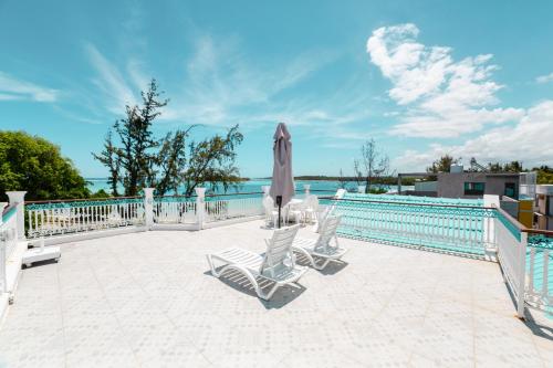 a patio with chairs and an umbrella next to a pool at Villa Bella Charming Beachfront Guesthouse in Blue Bay