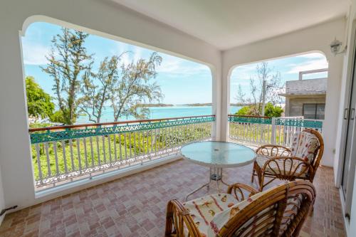 a balcony with a table and chairs and a view of the water at Villa Bella Charming Beachfront Guesthouse in Blue Bay