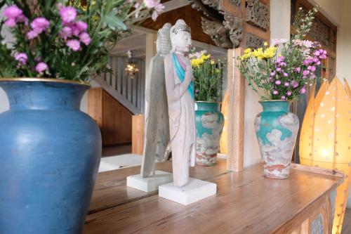 a statue of an angel sitting on a table with vases at BoHo Bingin Beach Bali in Uluwatu