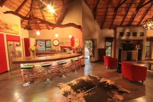 ein Wohnzimmer mit einer Bar mit roten Stühlen in der Unterkunft Call of the Wild Lodge in Hoedspruit
