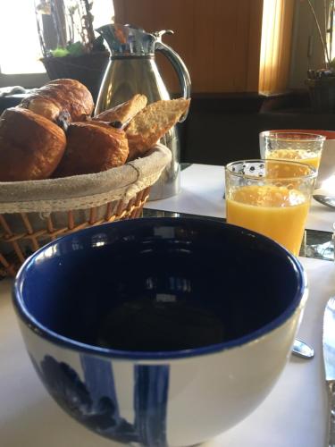 un tazón de pan y un vaso de zumo de naranja en Hôtel Bar Aux Armes D'Estaing - KB HOTEL GROUP, en Estaing