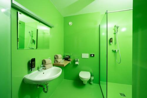 een groene badkamer met een wastafel en een toilet bij Hotel Greenrooms in Graz