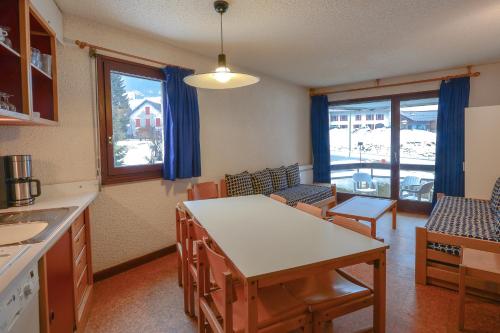 eine Küche mit einem Tisch und Stühlen im Zimmer in der Unterkunft VVF Les Monts Jura in Lélex