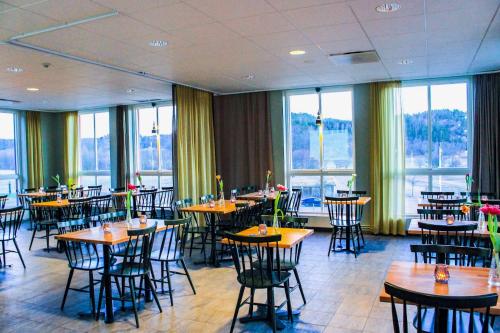 un restaurante con mesas, sillas y ventanas en Nordens Ark Hotell, en Stranderäng