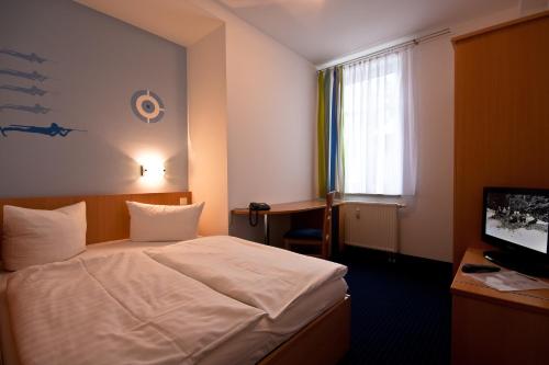 Schlafzimmer mit einem Bett, einem Schreibtisch und einem TV in der Unterkunft Outdoor Inn Sporthotel Steinach in Steinach