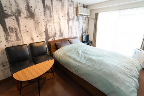 a bedroom with a bed and a table and chairs at SONIC APARTMENT HOTEL in Dazaifu