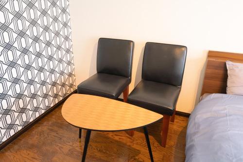 two chairs and a table in a room with a bed at SONIC APARTMENT HOTEL in Dazaifu