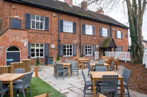 a patio with tables and chairs in front of a building at The King's Head by Innkeeper's Collection in Wellesbourne Hastings