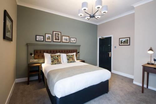 a bedroom with a large bed and a chandelier at The King's Head by Innkeeper's Collection in Wellesbourne Hastings