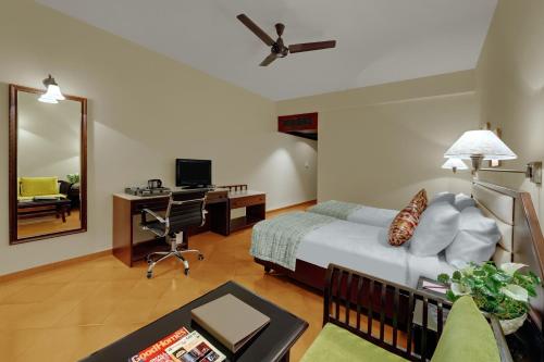 a bedroom with a bed and a desk and a mirror at The Fern Kesarval Hotel & Spa, Verna Plateau - Goa in Verna