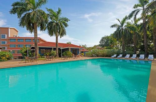 une grande piscine avec des chaises et des palmiers dans l'établissement The Fern Kesarval Hotel & Spa, Verna Plateau - Goa, à Verna