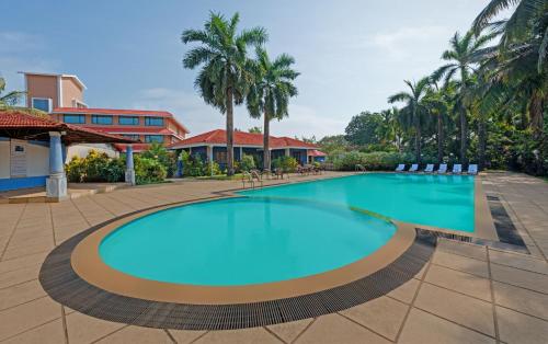 a swimming pool in a resort with chairs and palm trees at The Fern Kesarval Hotel & Spa, Verna Plateau - Goa in Verna