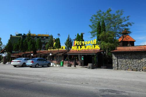 a sign for a restaurant with cars parked in front of it at Medzhybozhskiy Zamok in Tribukhovtsy