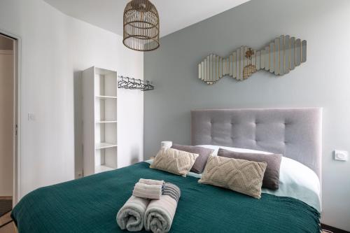 een slaapkamer met een groen bed en handdoeken bij Joli T2, gare, intra-muros & plage à proximité in Saint-Malo